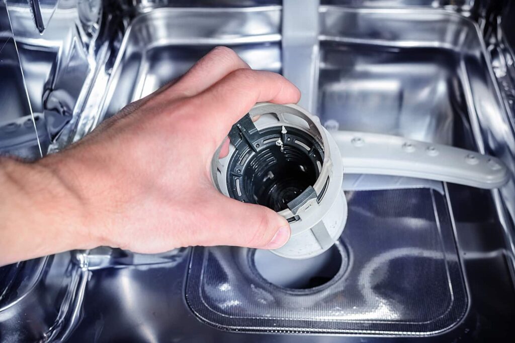 person cleaning dishwasher filter